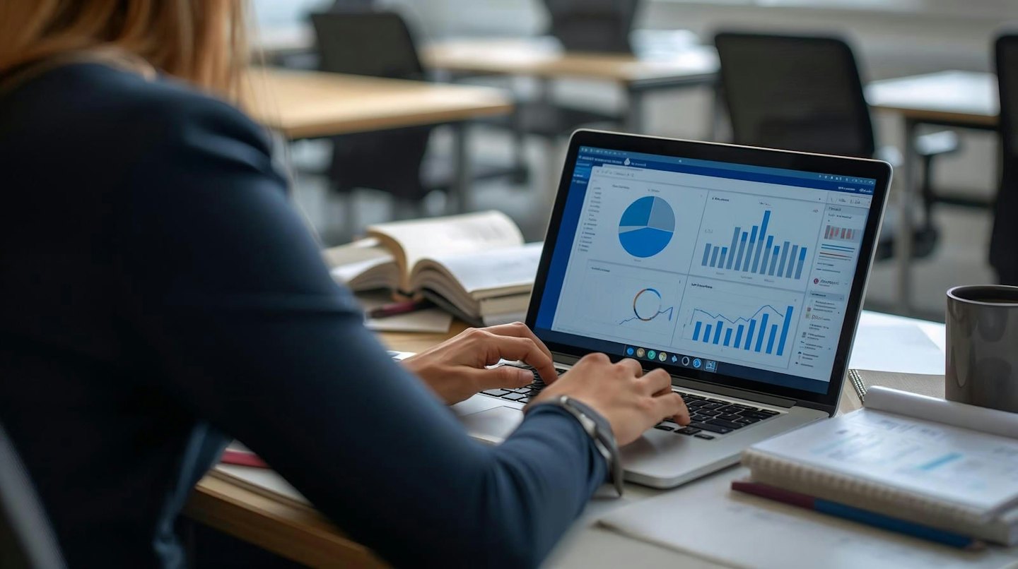 Person typing on laptop with business charts on screen.